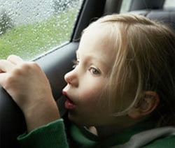 Photo of a young girl looking out a car window